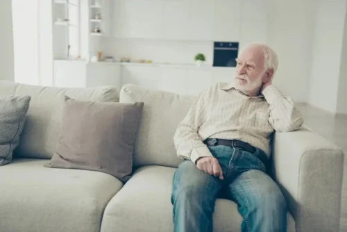 Senior man with chronic condition resting on a couch at home.