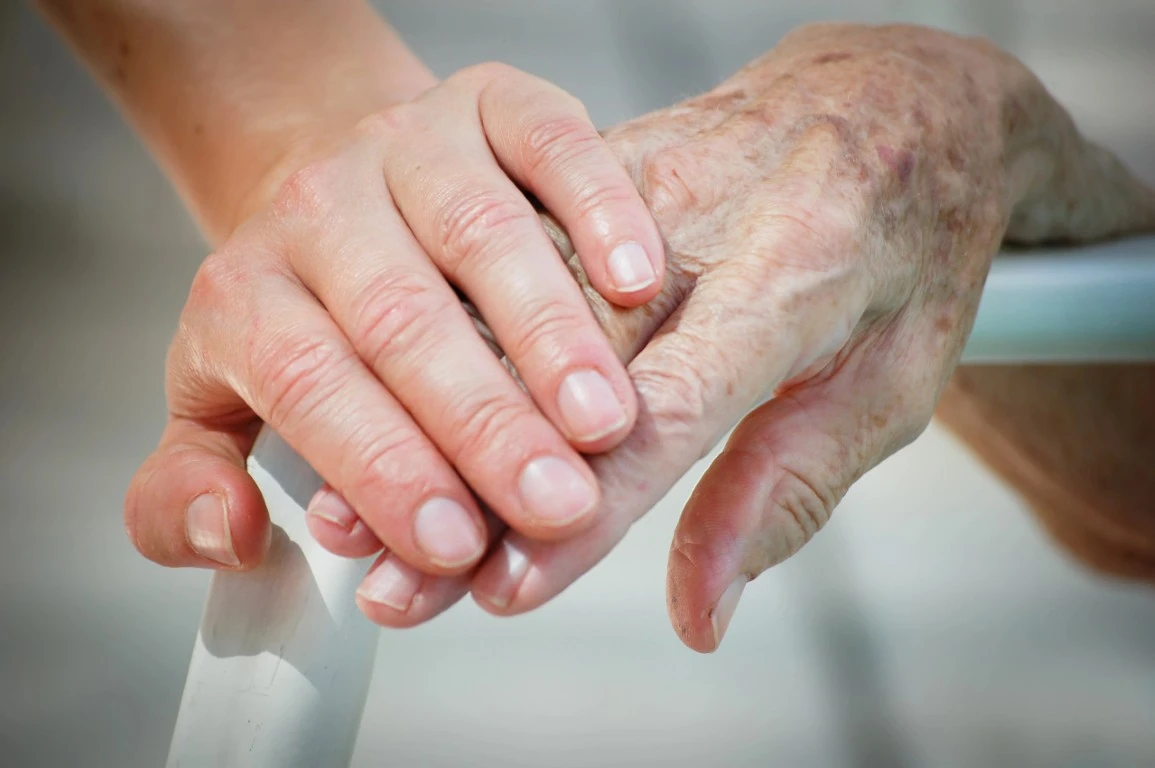 Hands of a younger person holding an elder's hand, symbolizing companionship care.